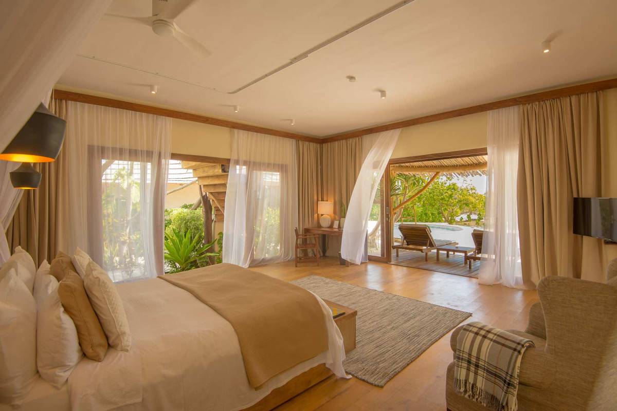 Blick auf das Bett im Schlafzimmer im Erdgeschoss einer Villa im Zanzibar White Sand bei geöffneter Terrassentür